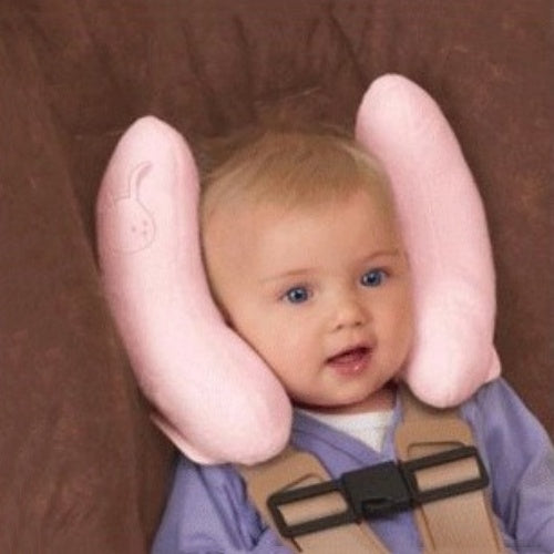 Baby wearing a pink Baby Head-Shaped Banana Pillow against a brown background