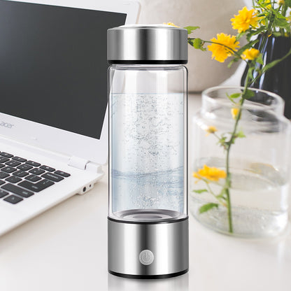 HydraPure™ Hydrogen Water Bottle on a desk with a laptop and flowers in the background