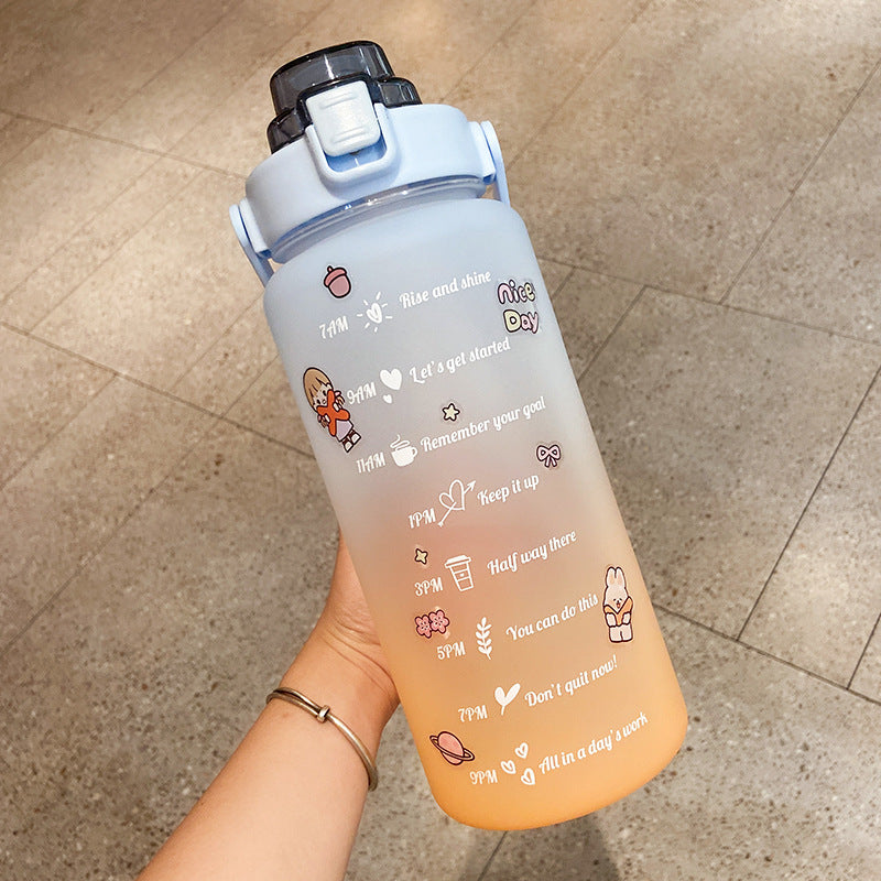HydraTrack™ 2L Water Bottle with motivational text and graphics held by a hand on a tiled floor.