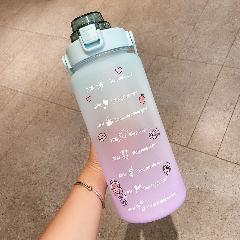 HydraTrack™ 2L Water Bottle with text and icons held by a hand on a tiled floor.