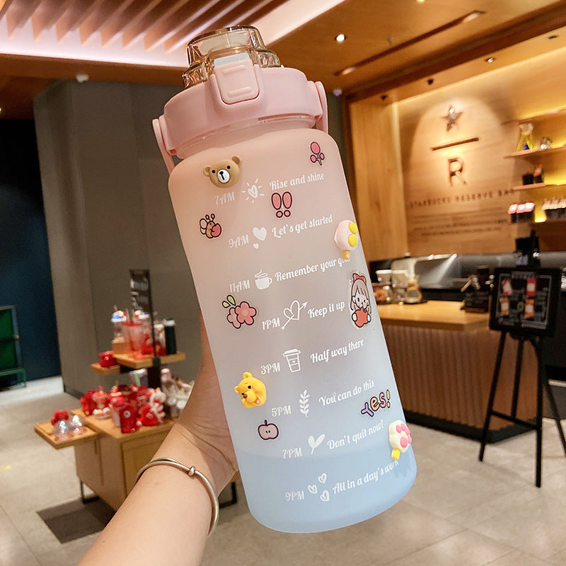 HydraTrack™ 2L Water Bottle with cartoon designs held in a hand, indoor setting