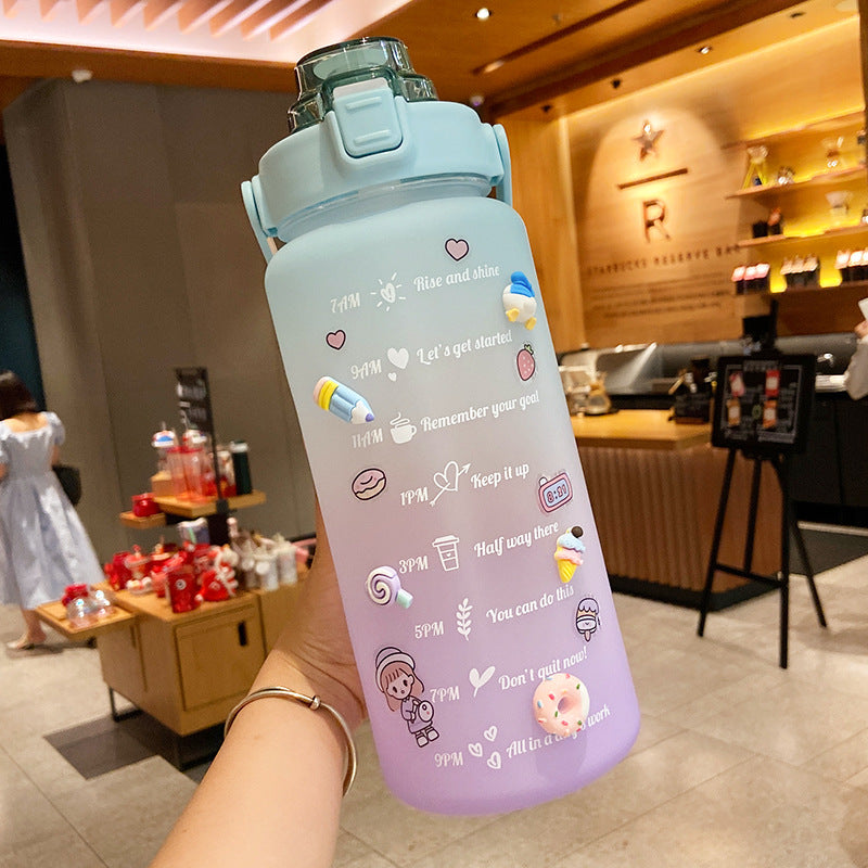 HydraTrack™ 2L Water Bottle with cartoon designs held in a hand, indoor setting
